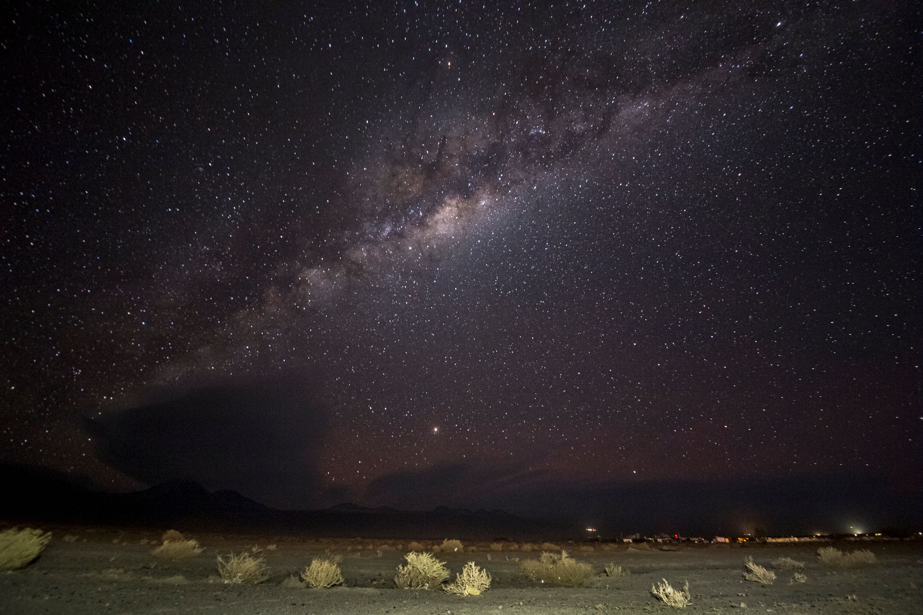 Vast starfield and Milky Way arc stretching over desert salt flats